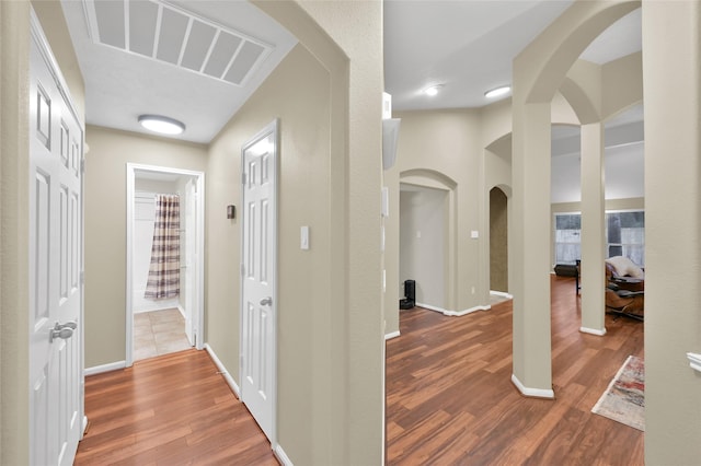 hall with visible vents, baseboards, and wood finished floors