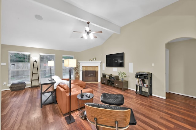 living room featuring baseboards, lofted ceiling with beams, a tile fireplace, wood finished floors, and arched walkways