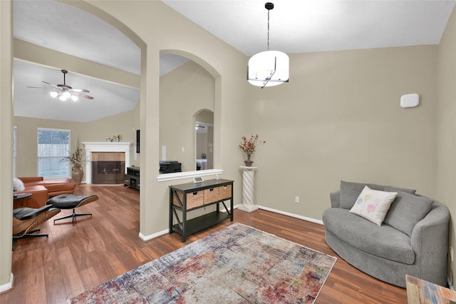 living area featuring lofted ceiling, wood finished floors, baseboards, and a tile fireplace