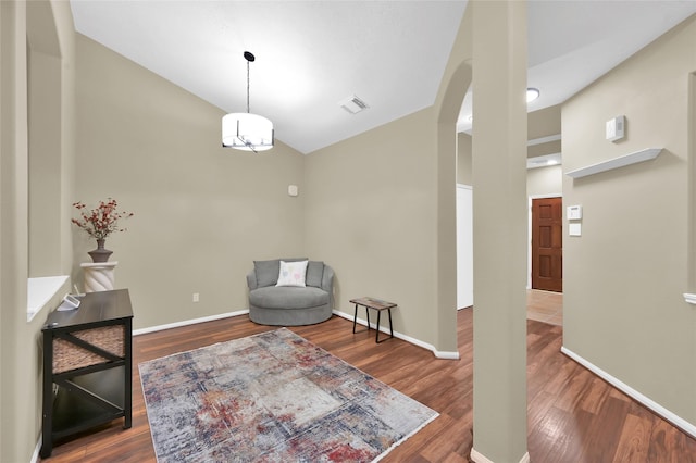 sitting room with visible vents, baseboards, vaulted ceiling, wood finished floors, and arched walkways