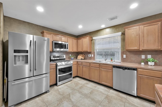 kitchen with visible vents, a sink, stainless steel appliances, light countertops, and tasteful backsplash