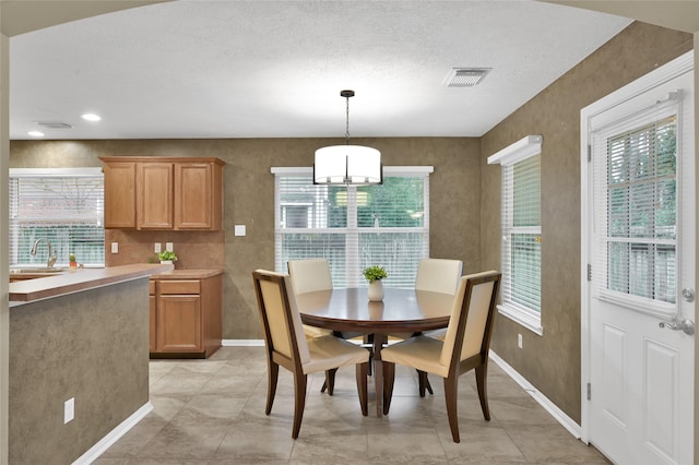 dining space featuring visible vents, a textured ceiling, and baseboards