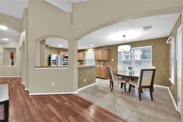 dining space with visible vents, baseboards, light wood-style floors, and an inviting chandelier