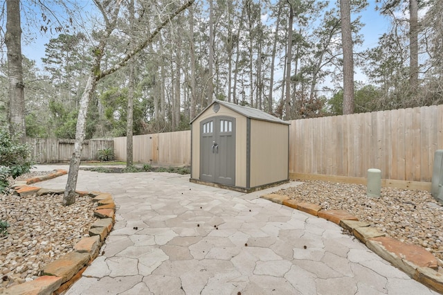 view of patio / terrace featuring an outdoor structure, a fenced backyard, and a shed