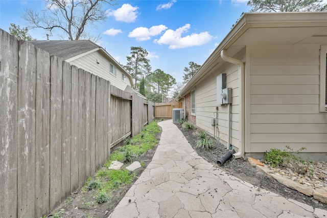 view of property exterior with brick siding, central air condition unit, and fence