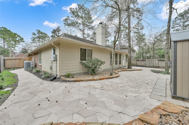 view of home's exterior with cooling unit, a patio, a fenced backyard, and a chimney