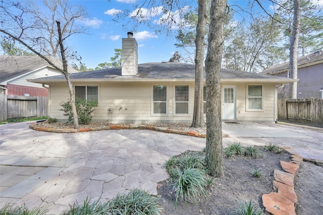 back of house featuring a patio area, fence, and a chimney