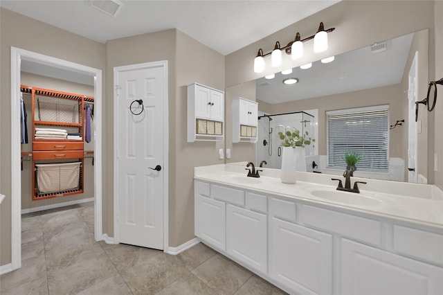 bathroom featuring double vanity, visible vents, walk in shower, and a sink