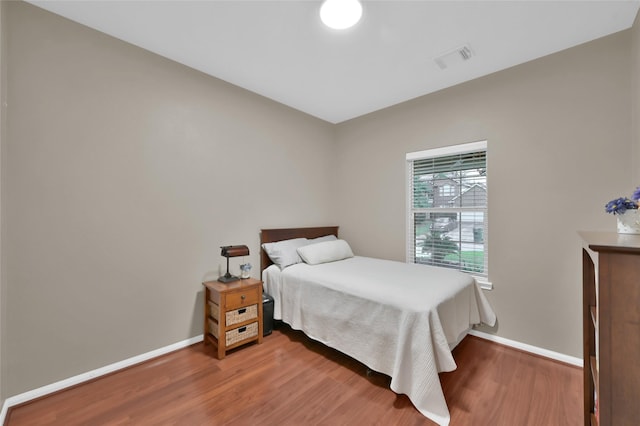 bedroom featuring visible vents, wood finished floors, and baseboards