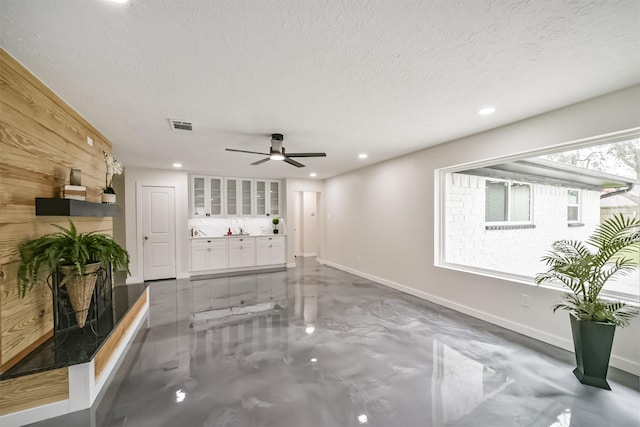 unfurnished living room featuring visible vents, baseboards, recessed lighting, a textured ceiling, and a ceiling fan