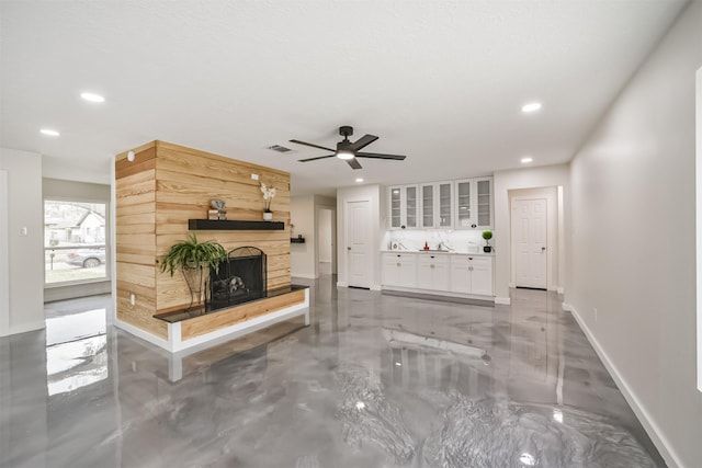 living room with recessed lighting, visible vents, baseboards, and a fireplace with raised hearth