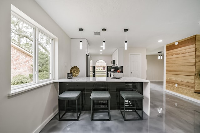 kitchen with visible vents, baseboards, finished concrete floors, and white cabinets