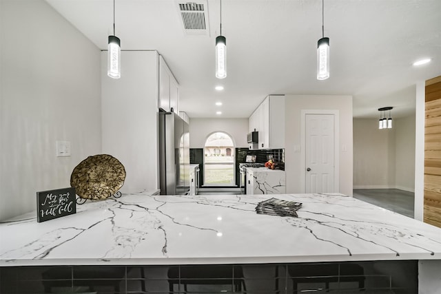 kitchen with light stone counters, visible vents, appliances with stainless steel finishes, and white cabinetry