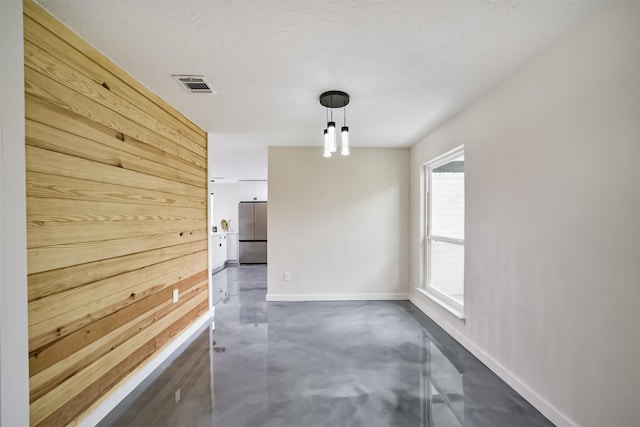 interior space with wooden walls, baseboards, visible vents, finished concrete floors, and a textured ceiling