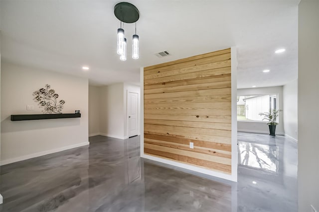 unfurnished room featuring visible vents, baseboards, finished concrete floors, wood walls, and recessed lighting