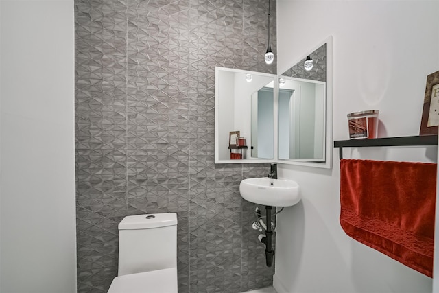 half bath featuring toilet and tile walls