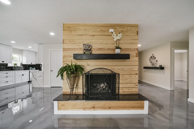 living area featuring recessed lighting, baseboards, a textured ceiling, and a fireplace with raised hearth