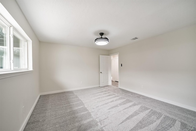 empty room with visible vents, carpet floors, and baseboards