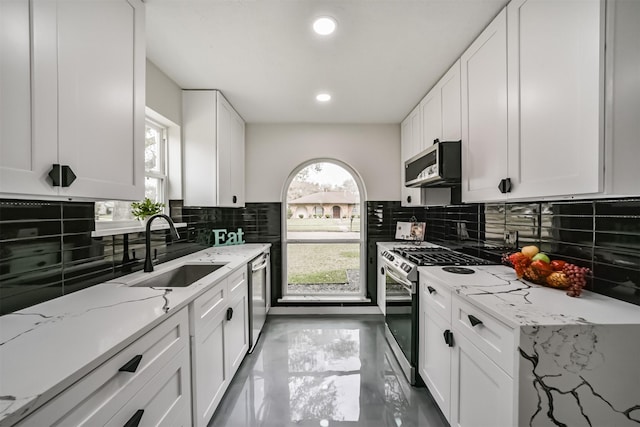 kitchen with a sink, stainless steel appliances, backsplash, and white cabinets