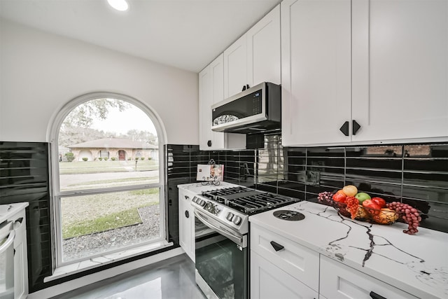 kitchen featuring decorative backsplash, appliances with stainless steel finishes, white cabinets, and light countertops