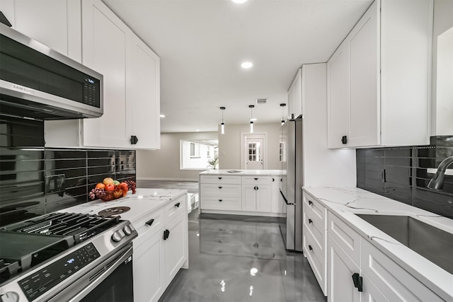 kitchen with tasteful backsplash, light stone countertops, appliances with stainless steel finishes, white cabinets, and a sink