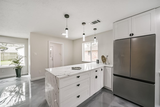 kitchen featuring visible vents, white cabinetry, freestanding refrigerator, a peninsula, and light stone countertops