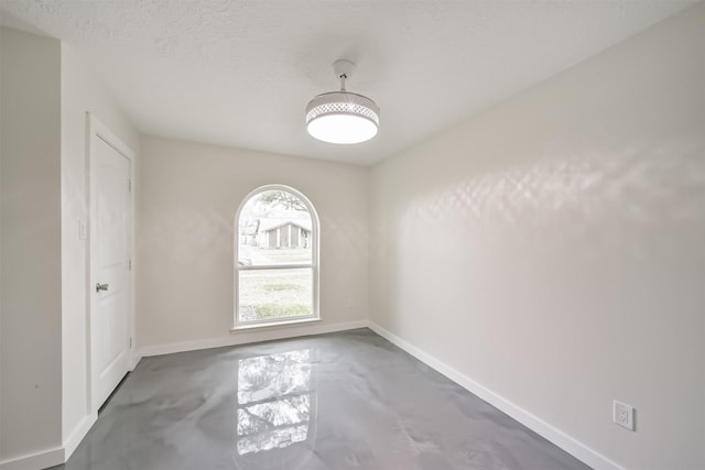 unfurnished room featuring baseboards, concrete floors, and a textured ceiling