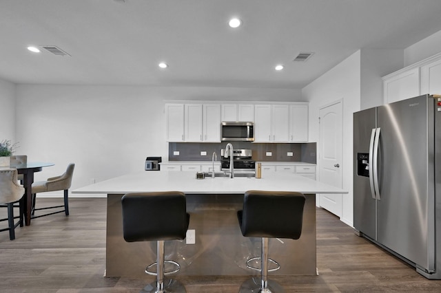 kitchen with a sink, visible vents, appliances with stainless steel finishes, and dark wood-style floors