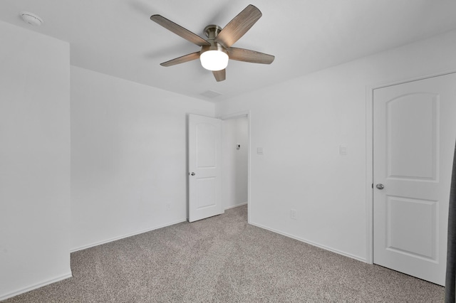 carpeted spare room with baseboards and a ceiling fan