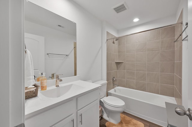 bathroom featuring vanity, wood finished floors, visible vents, bathing tub / shower combination, and toilet