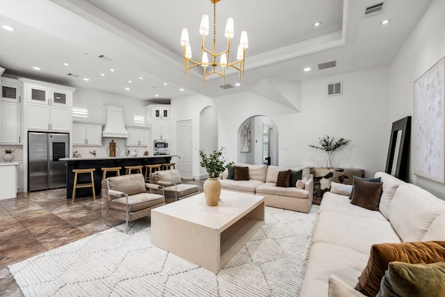 living room with arched walkways, visible vents, a tray ceiling, and a towering ceiling