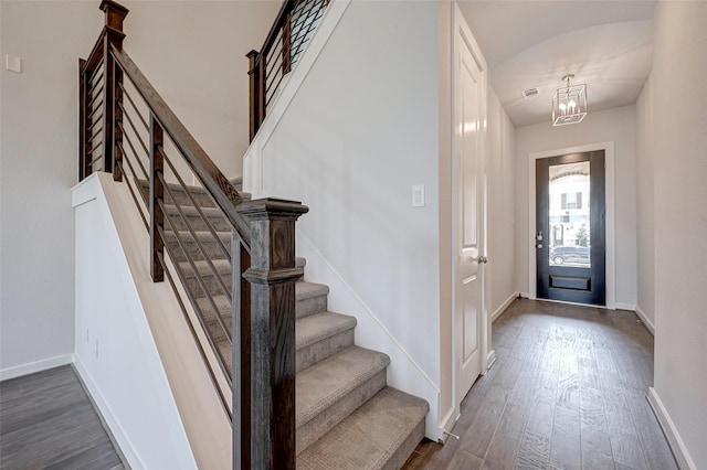 foyer with stairs, dark wood-type flooring, visible vents, and baseboards