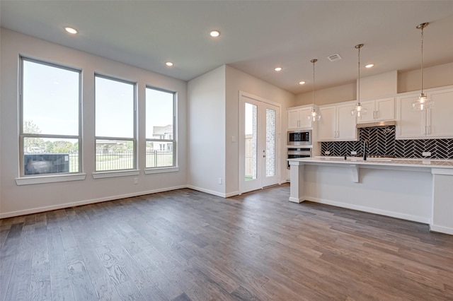 kitchen with dark wood finished floors, plenty of natural light, stainless steel appliances, and light countertops