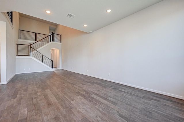 unfurnished living room featuring visible vents, baseboards, dark wood finished floors, stairway, and recessed lighting