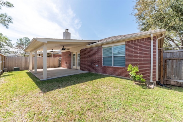 rear view of property with brick siding, ceiling fan, a yard, a fenced backyard, and a patio area