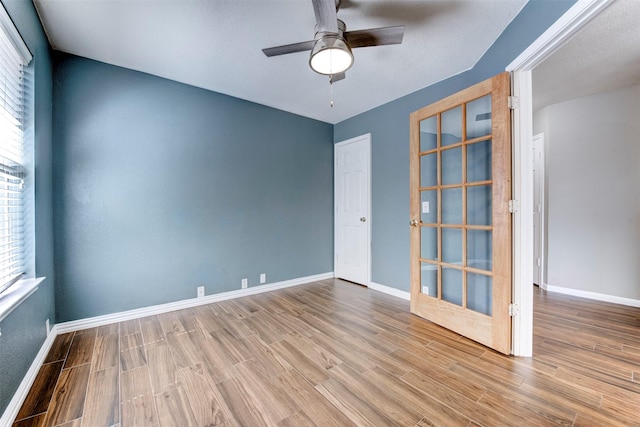 empty room with baseboards, a ceiling fan, and wood finished floors