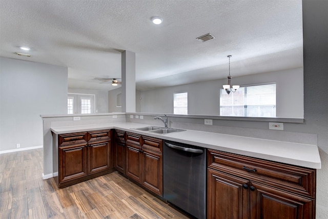 kitchen featuring wood finished floors, visible vents, a sink, stainless steel dishwasher, and ceiling fan with notable chandelier