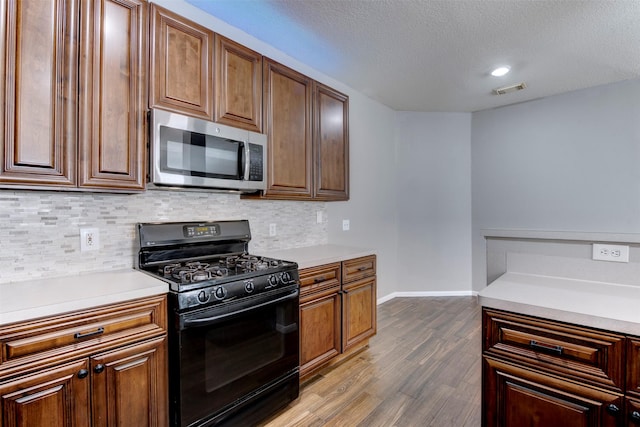 kitchen with stainless steel microwave, gas stove, light countertops, and visible vents