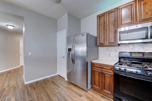 kitchen with tasteful backsplash, light wood-style flooring, stainless steel appliances, and light countertops