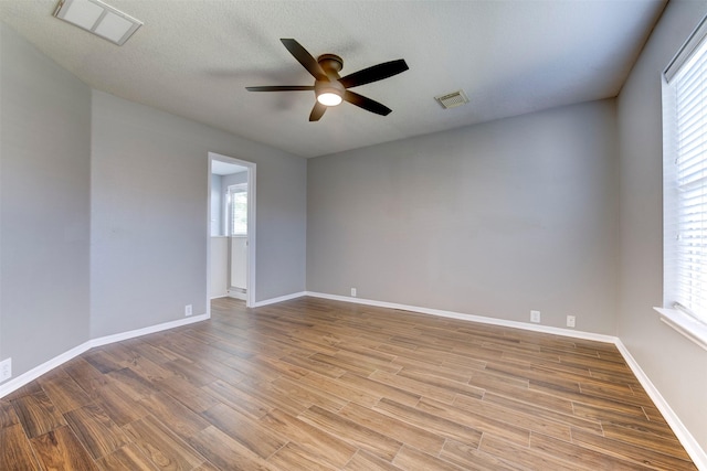 unfurnished room with visible vents, wood finished floors, baseboards, and ceiling fan