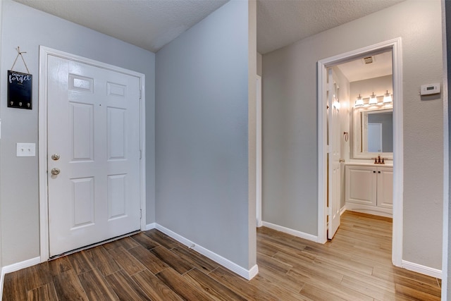 entrance foyer featuring a textured ceiling, baseboards, and wood finished floors