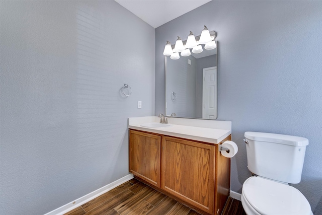 half bath with vanity, toilet, wood finished floors, and baseboards