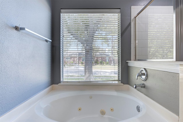 bathroom with a tub with jets and a textured wall