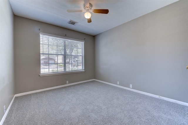 carpeted spare room featuring visible vents, baseboards, and ceiling fan