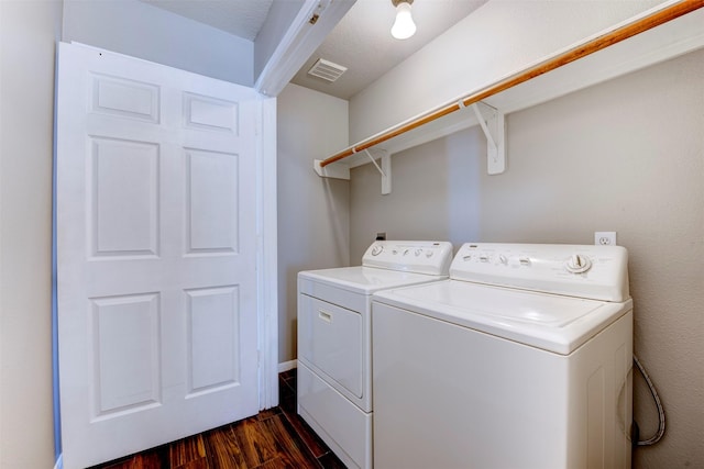 laundry room with washing machine and clothes dryer, visible vents, laundry area, and dark wood-type flooring