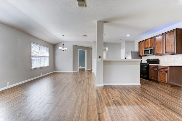 kitchen with open floor plan, backsplash, stainless steel appliances, and wood finished floors