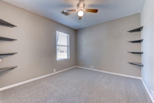 spare room featuring visible vents, a textured ceiling, carpet flooring, baseboards, and ceiling fan