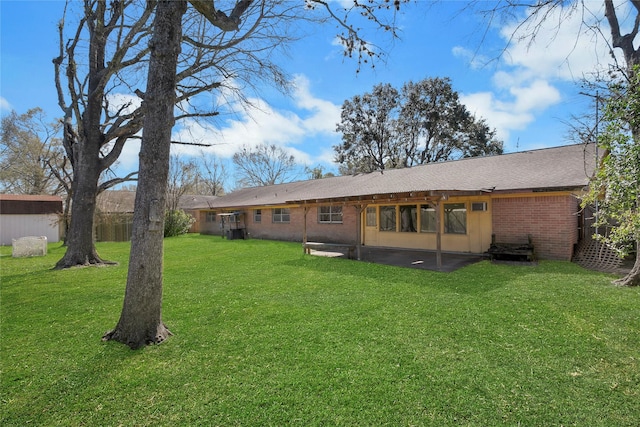 rear view of house featuring a patio, a lawn, and brick siding