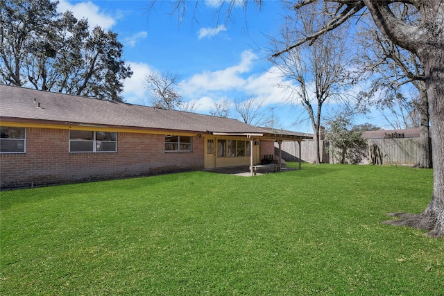 back of property with a patio area, fence, a lawn, and brick siding