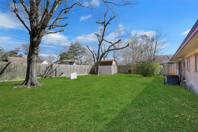 view of yard with an outbuilding, a fenced backyard, and a shed